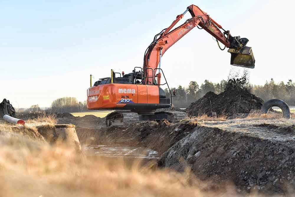 Orange grävskopa med MEMAs logga