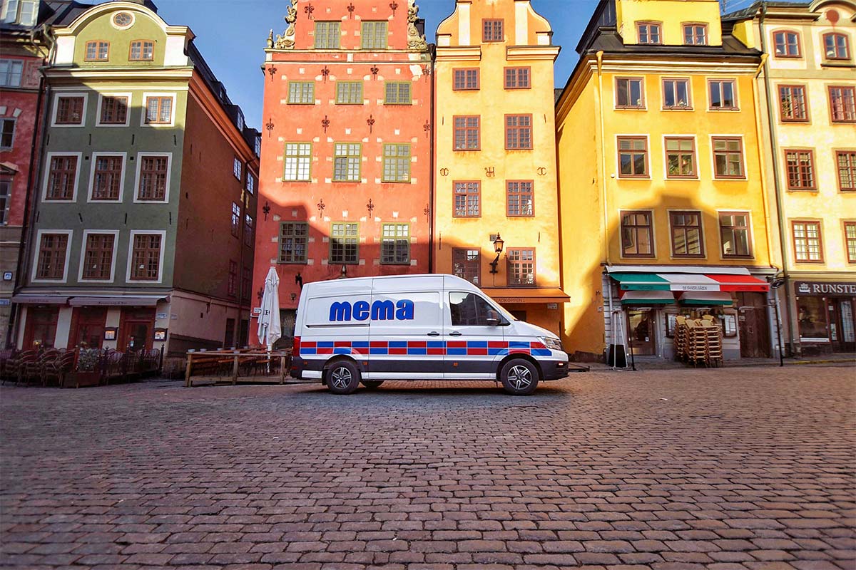 En vit skåpbil framför färgglada hus i Gamla Stan, Stockholm